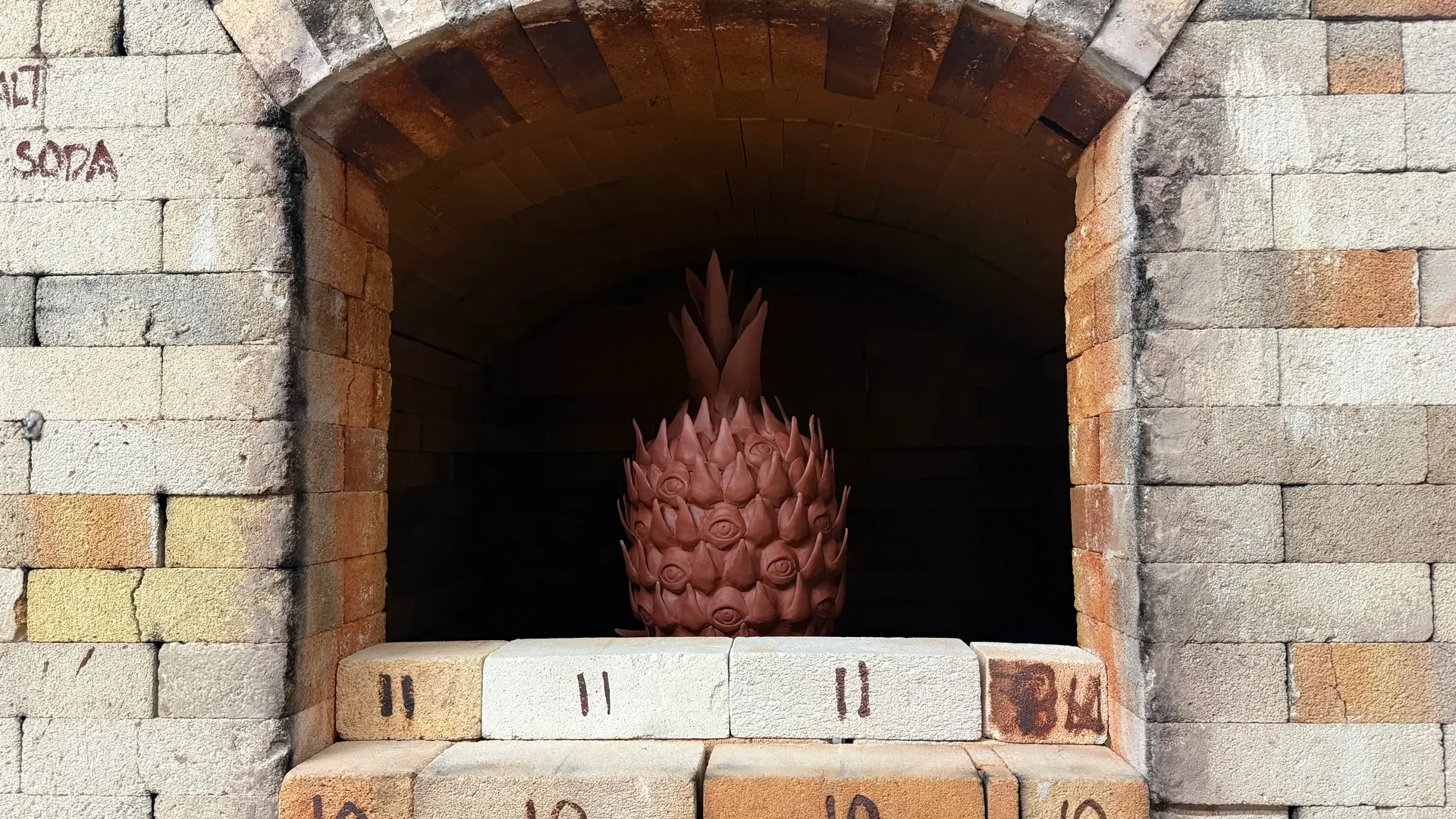 The head of the Pinya sculpture peaking past the kiln bricks.